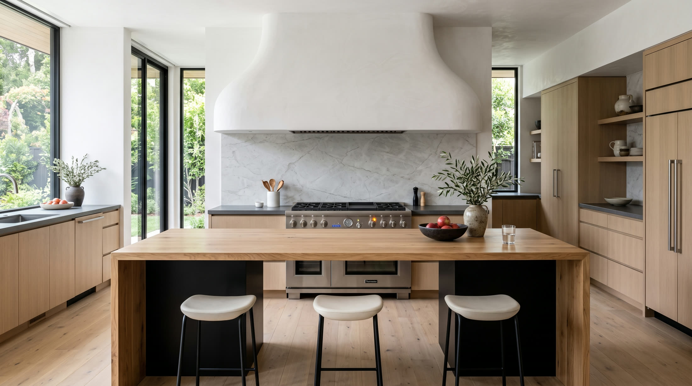 Thermador range beneath a plaster hood in a kitchen under Noble care